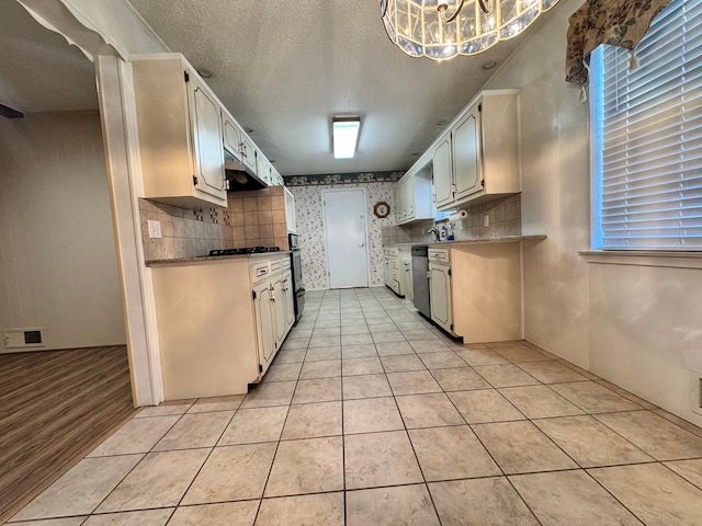 kitchen with stainless steel dishwasher, light tile patterned floors, a textured ceiling, and tasteful backsplash