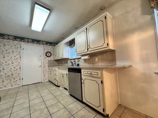 kitchen featuring stainless steel dishwasher, light tile patterned floors, and a textured ceiling