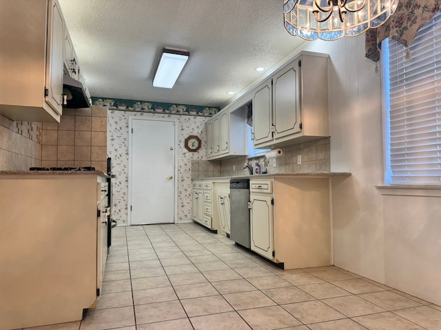 kitchen featuring dishwasher, light tile patterned flooring, a textured ceiling, and a chandelier