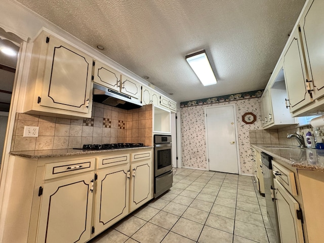 kitchen featuring black gas cooktop, oven, decorative backsplash, a textured ceiling, and light tile patterned flooring