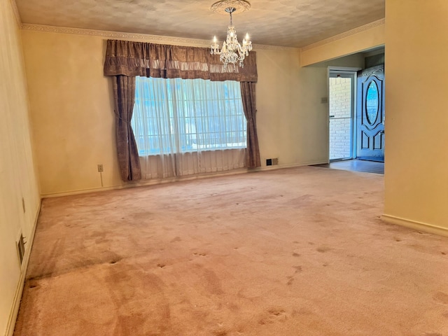 empty room featuring carpet floors, crown molding, and a notable chandelier