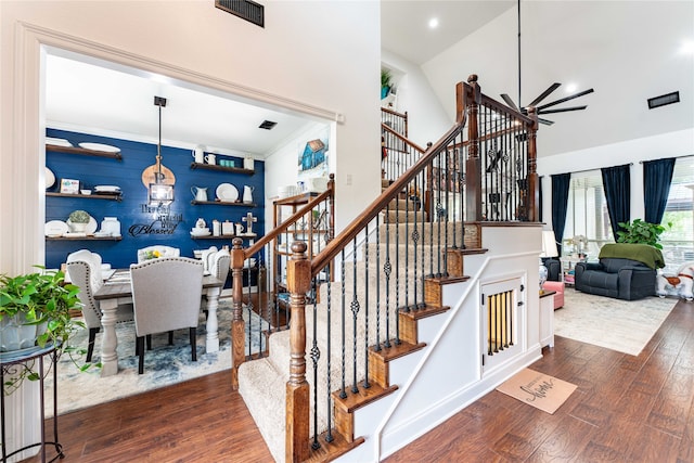 stairway with wood-type flooring, lofted ceiling, and ornamental molding