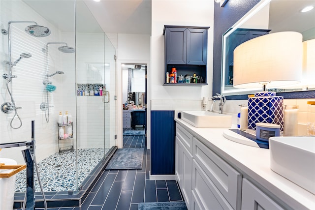 bathroom featuring tile patterned flooring, vanity, a shower with door, and tile walls