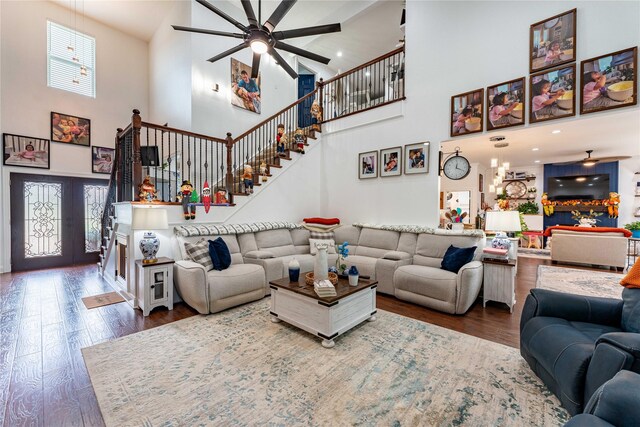 living room featuring ceiling fan, french doors, a towering ceiling, and wood-type flooring