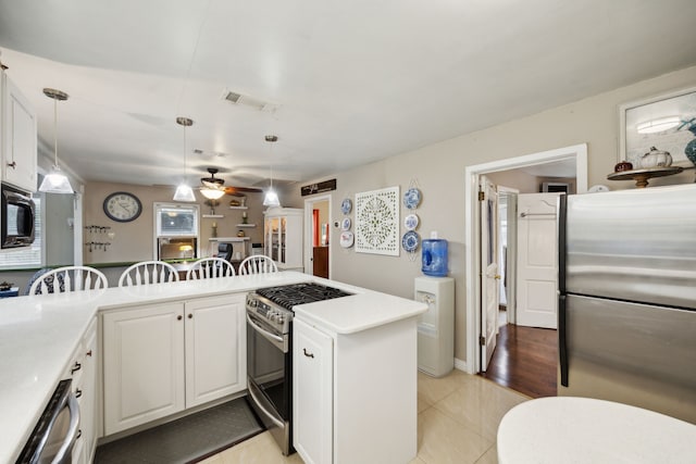 kitchen featuring pendant lighting, kitchen peninsula, stainless steel appliances, and white cabinets