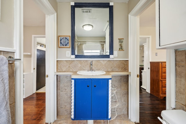 bathroom with hardwood / wood-style floors, vanity, a shower, and toilet