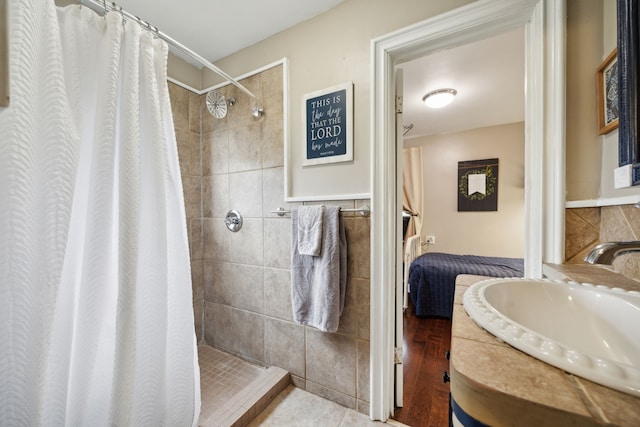 bathroom with tile walls, curtained shower, hardwood / wood-style floors, and vanity