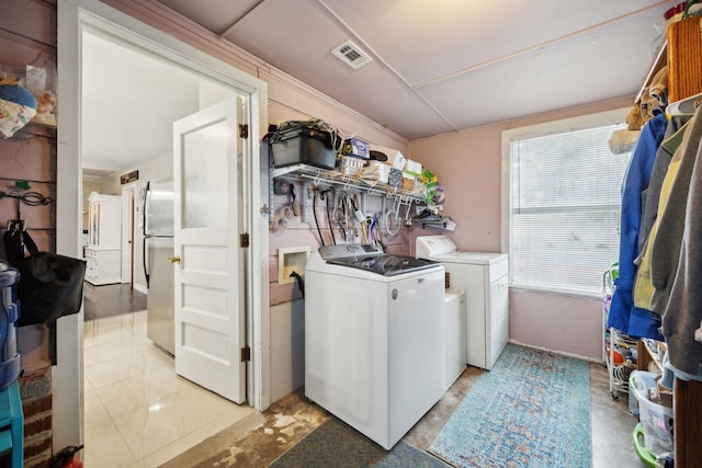 laundry room with independent washer and dryer and light tile patterned flooring