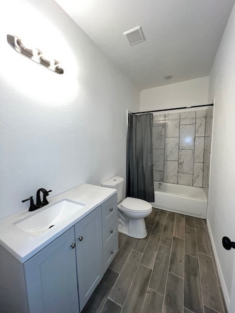 full bathroom featuring toilet, vanity, hardwood / wood-style floors, and shower / bathtub combination with curtain