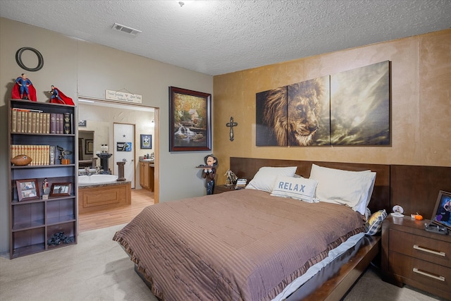 carpeted bedroom with a textured ceiling and ensuite bath