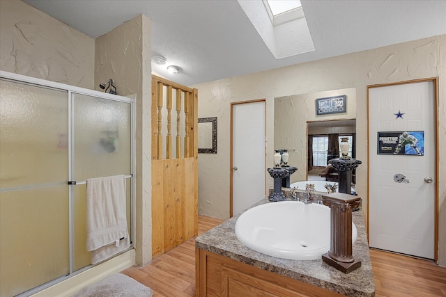 bathroom with wood-type flooring, shower with separate bathtub, a textured ceiling, and a skylight