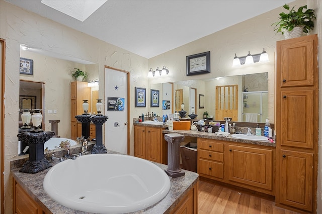 bathroom featuring vanity, hardwood / wood-style floors, a skylight, and shower with separate bathtub