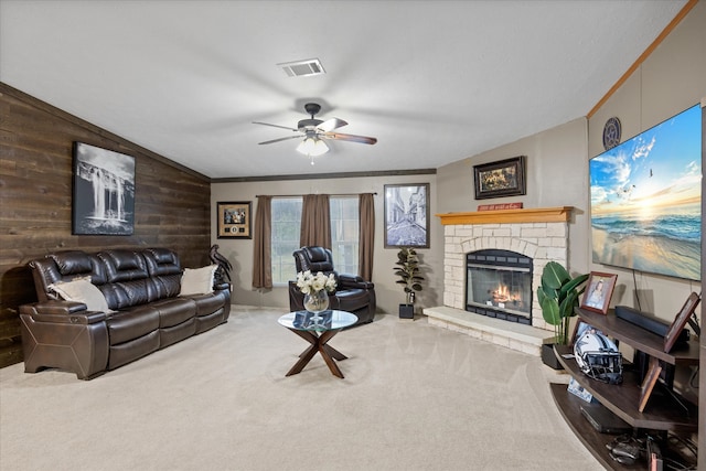 carpeted living room with crown molding, a fireplace, ceiling fan, and wood walls