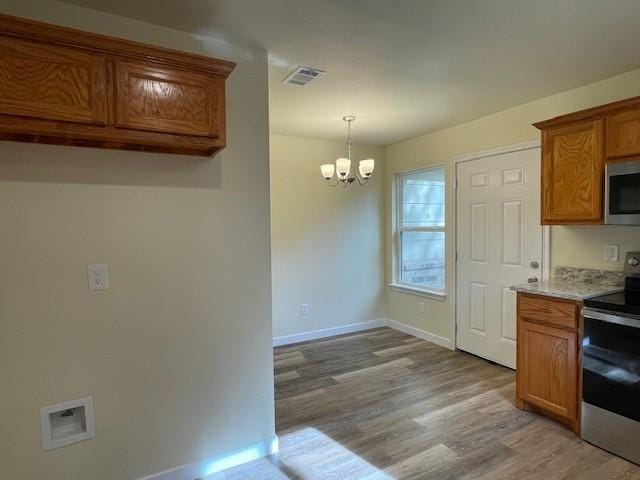 kitchen with decorative light fixtures, light hardwood / wood-style floors, a notable chandelier, and appliances with stainless steel finishes