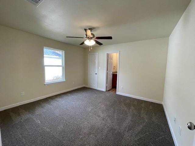 empty room with ceiling fan and dark carpet