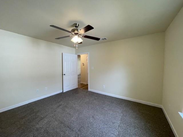 spare room with dark colored carpet and ceiling fan