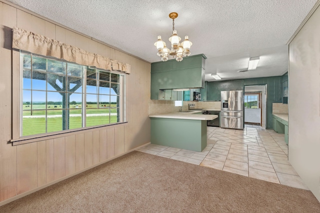 kitchen with green cabinetry, stainless steel appliances, kitchen peninsula, light carpet, and backsplash