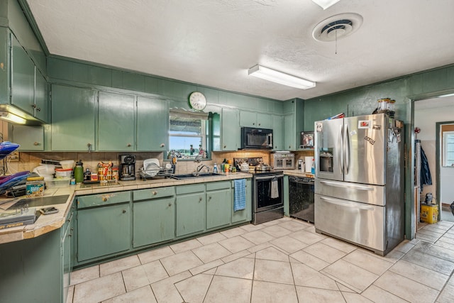 kitchen with green cabinetry, appliances with stainless steel finishes, and sink