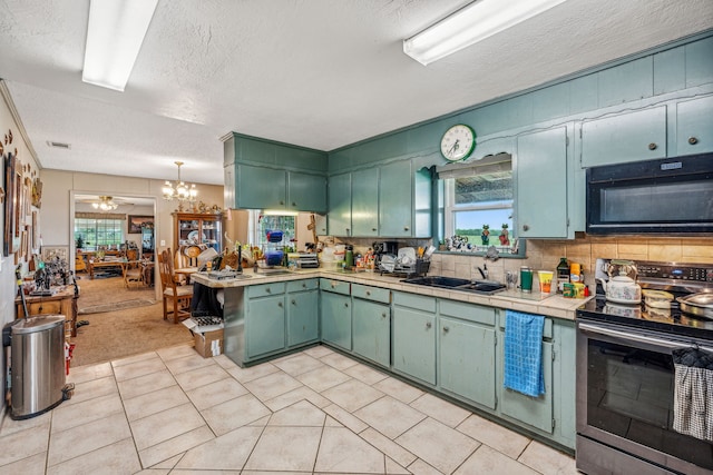 kitchen featuring tasteful backsplash, stainless steel range with electric cooktop, a textured ceiling, tile counters, and ceiling fan