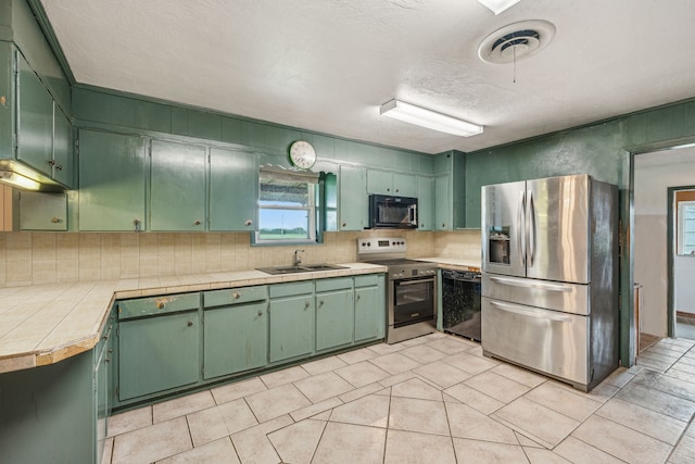 kitchen with tile countertops, sink, black appliances, and green cabinetry