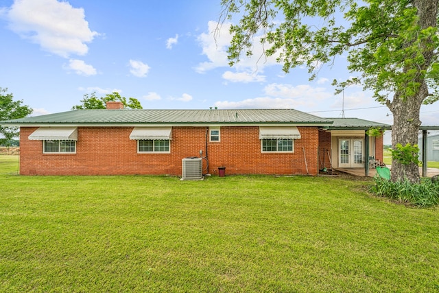 rear view of property featuring cooling unit and a lawn