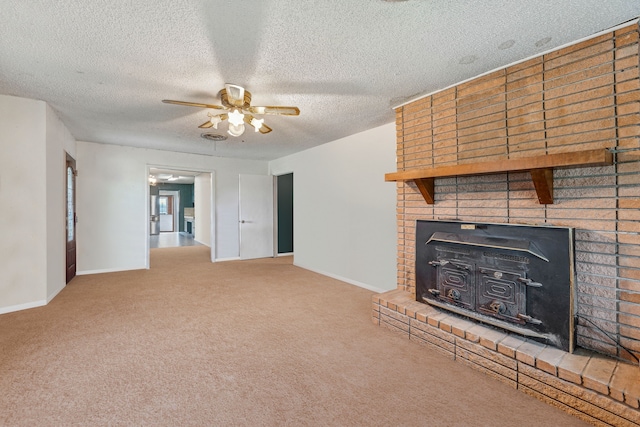 unfurnished living room with ceiling fan, a textured ceiling, carpet flooring, and a wood stove