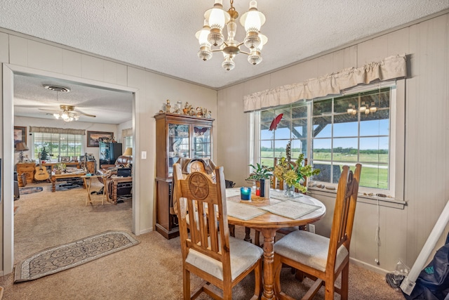 carpeted dining area featuring ceiling fan with notable chandelier, a textured ceiling, and wooden walls