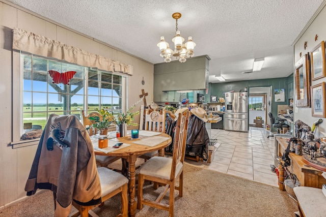 tiled dining space with plenty of natural light, a notable chandelier, and a textured ceiling