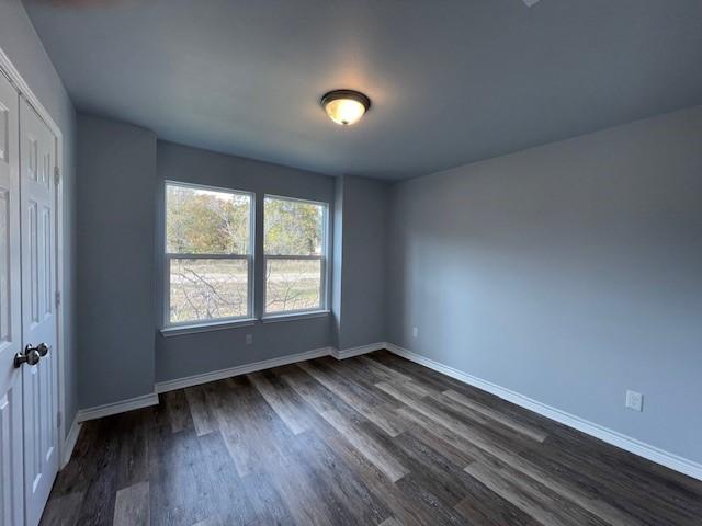 unfurnished bedroom with dark hardwood / wood-style flooring and a closet