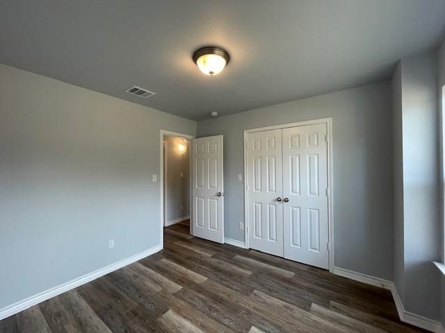 unfurnished bedroom featuring a closet and dark wood-type flooring