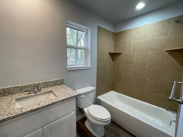 full bathroom with hardwood / wood-style floors, vanity, toilet, and tiled shower / bath