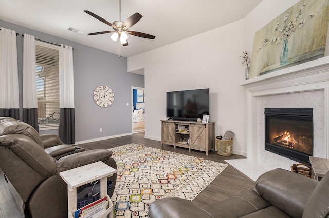 living room featuring a high end fireplace, dark hardwood / wood-style flooring, and ceiling fan