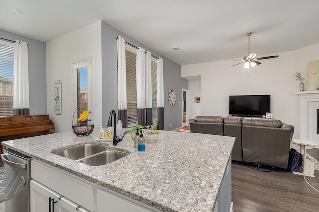 kitchen with white cabinetry, sink, ceiling fan, light stone counters, and a kitchen island with sink