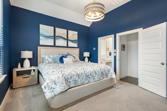 carpeted bedroom featuring ensuite bathroom, an inviting chandelier, and lofted ceiling