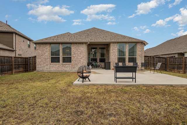 rear view of house with a yard, a patio, and an outdoor fire pit