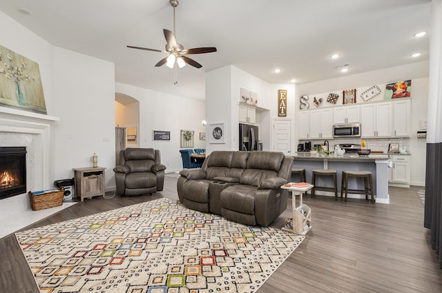 living room featuring ceiling fan, a fireplace, and dark hardwood / wood-style floors