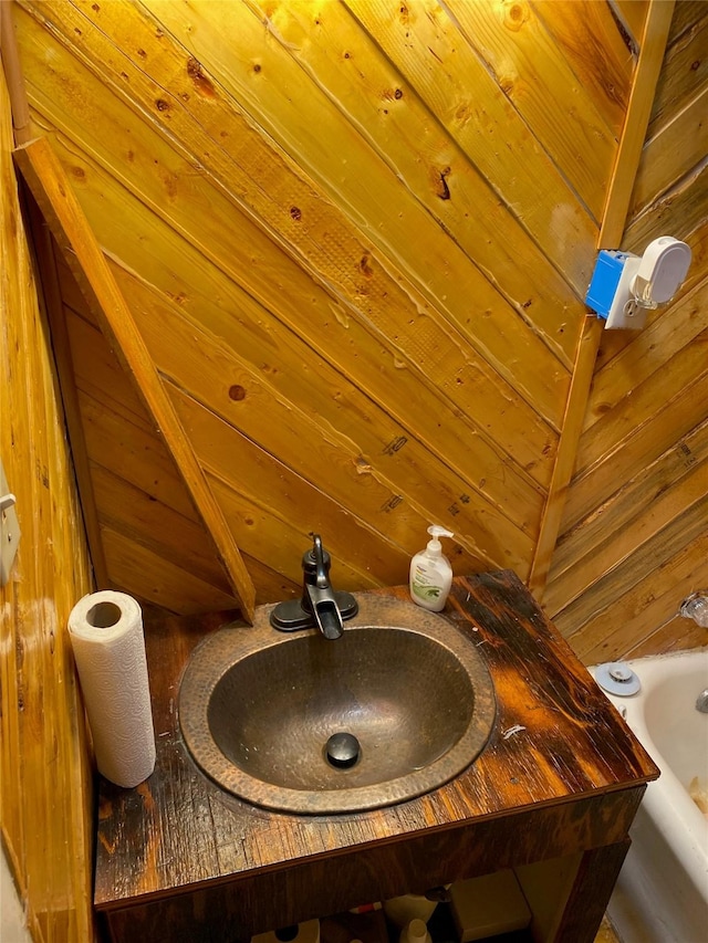 room details with a bathtub, wooden walls, and sink