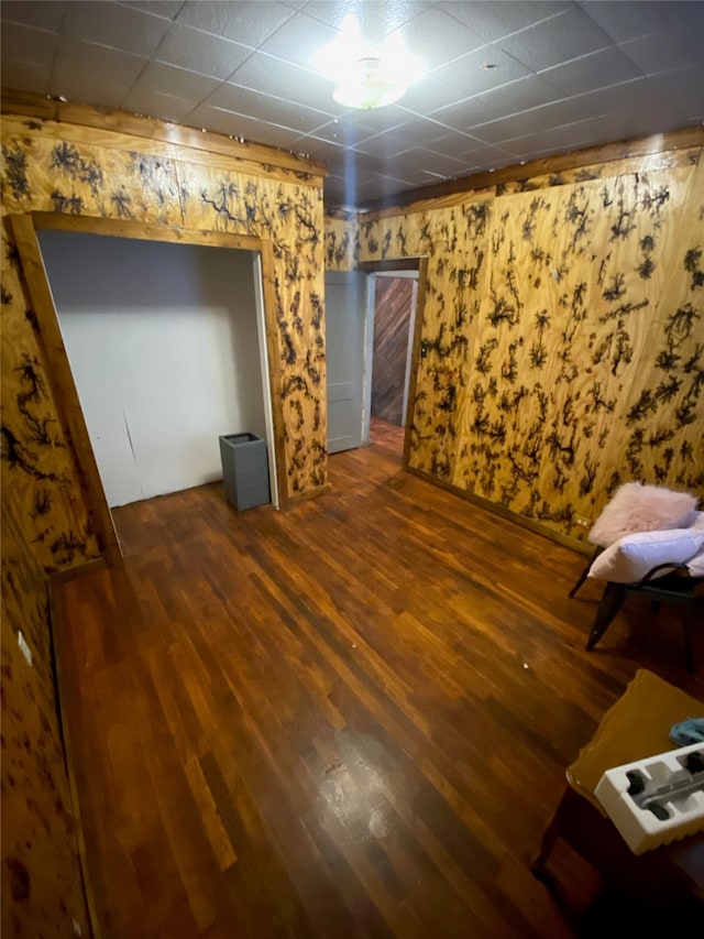 interior space with dark wood-type flooring and a drop ceiling