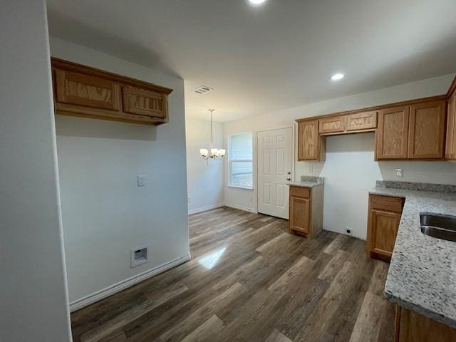 kitchen with light stone countertops, hanging light fixtures, dark hardwood / wood-style floors, and a notable chandelier