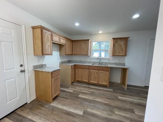 kitchen with light stone countertops, wood-type flooring, and sink