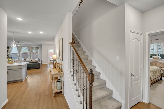 stairs with wood-type flooring, a healthy amount of sunlight, and ceiling fan