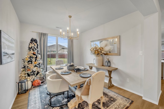 dining area featuring light wood-type flooring and an inviting chandelier