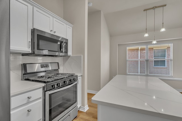 kitchen with light hardwood / wood-style floors, light stone counters, white cabinets, hanging light fixtures, and appliances with stainless steel finishes