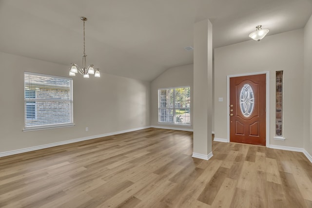 entrance foyer featuring an inviting chandelier, vaulted ceiling, and light hardwood / wood-style flooring