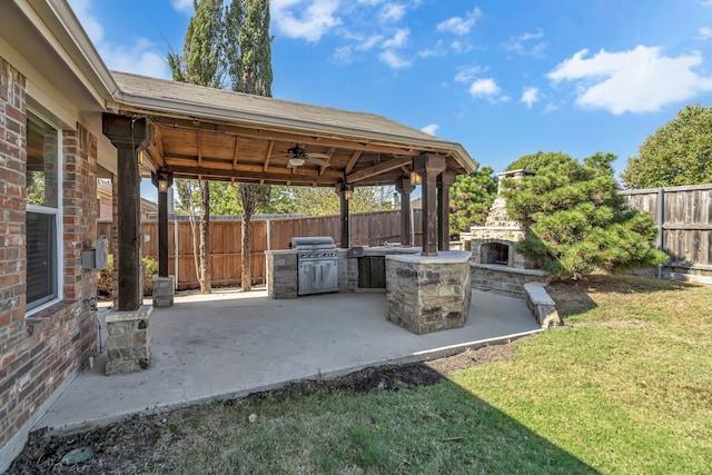 view of patio / terrace featuring an outdoor stone fireplace, a grill, ceiling fan, area for grilling, and a gazebo