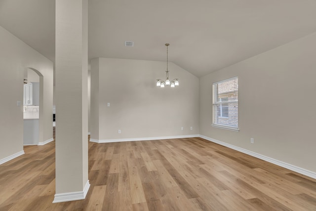 empty room with light hardwood / wood-style flooring, vaulted ceiling, and a notable chandelier