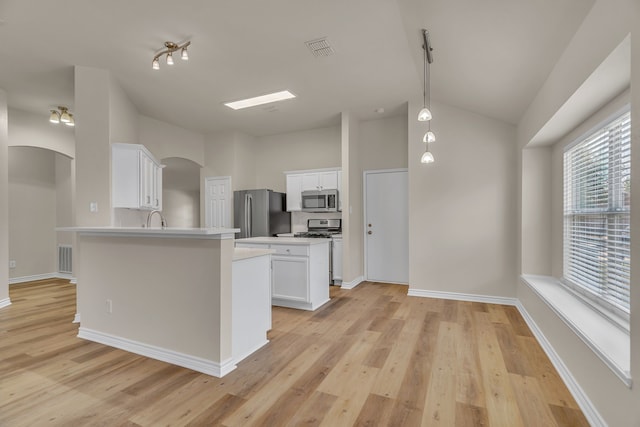 kitchen featuring stainless steel appliances, kitchen peninsula, white cabinetry, light hardwood / wood-style flooring, and decorative light fixtures