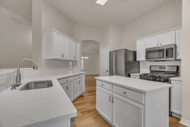 kitchen with light hardwood / wood-style flooring, a kitchen island, white cabinetry, and stainless steel appliances