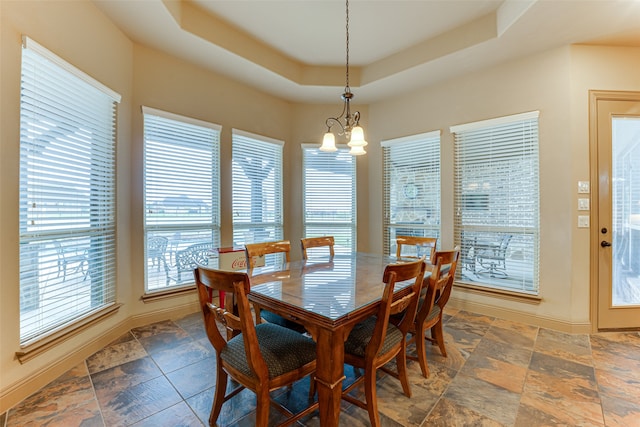 dining space with a chandelier and a raised ceiling