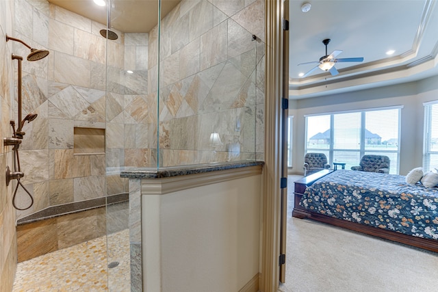 bathroom with crown molding, a tile shower, ceiling fan, and a raised ceiling